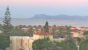Blick auf das Meer, Häuser und Palmen in der Unterkunft Nikos Apartments in Agia Marina