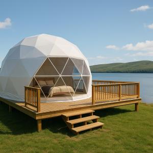 a dome house on a deck next to a body of water at Baddeck Domes in Baddeck