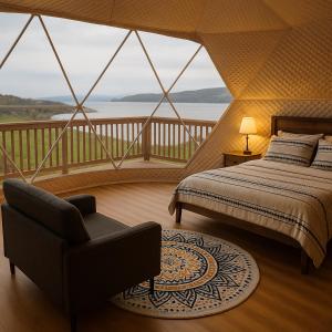 a bedroom with a bed and a chair and a balcony at Baddeck Domes in Baddeck