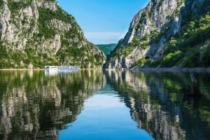 a boat in a river between two mountains at Greys Apartment in Kladovo