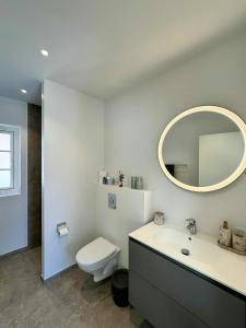 a bathroom with a sink and a toilet and a mirror at Holiday Home With Courtyard In Lille Skagen in Skagen