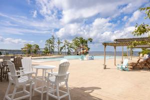 a pool with white chairs and a table and a swimming pool at Reider Room at the Inn, Occano Arnold Palmer Signature Golf 