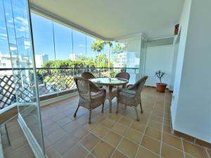 a balcony with a table and chairs and windows at Apartamento en primera línea de playa, Mi Capricho in Sitio de Calahonda
