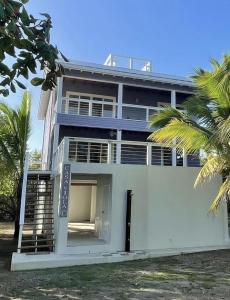 a large white building with a palm tree at Casa Viola - Utila in Utila