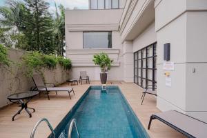 a house with a swimming pool next to a building at Elyseés Residencial Flipchave ELY000 in Joinville