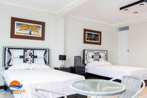 two beds in a room with a table and chairs at Descubre un lugar pensado para ti in Sechura