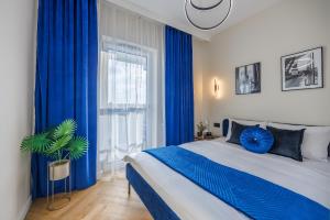 een slaapkamer met blauwe gordijnen en een bed met een plant bij Emihouse Riverside Apartments in Rzeszów