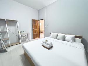 a bedroom with a large white bed and a table at I'm Home Narathiwat in Narathiwat
