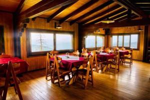 een eetkamer met tafels, stoelen en ramen bij Pensiunea Casa Ancutei in Ranca