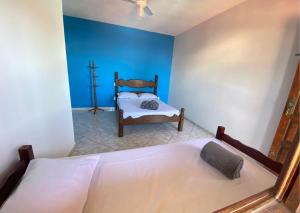 een slaapkamer met een bed en een blauwe muur bij Casa Vista do Sol, 5min de carro de Castelhanos, Frente Mar de Anchieta, 5 quartos-2 com ar condicionado lazer completo in Anchieta +28 foto's
