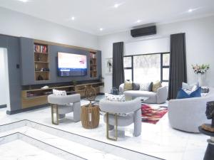 a living room with white furniture and a flat screen tv at Thaba Bosiu Villa in Naboomspruit