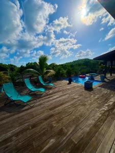 three chairs sitting on a deck next to a pool at Bel Kay in Rivière-Salée