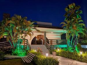 a house with palm trees and lights in front of it at Hotel Três Palmeiras in Gravatá
