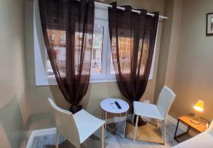 a table and chairs in front of a window with curtains at AS ROOMS Alicante in Alicante