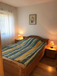 a bedroom with a bed with a striped comforter at Ferienwohnung EG rechts in Süderende +5 photos