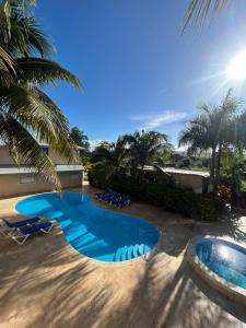 uma piscina de resort com espreguiçadeiras e palmeiras em Cabarete Town House em Cabarete