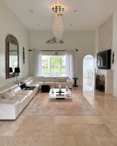 a living room with a white couch and a chandelier at Lux 4 bedroom home on lake with pool! in Coral Springs