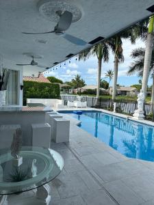 a swimming pool with palm trees next to a resort at Lux 4 bedroom home on lake with pool! in Coral Springs