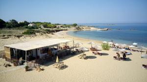a beach with umbrellas and people sitting on the sand at BEACH WHTE VILLAs one bedroom in Minia