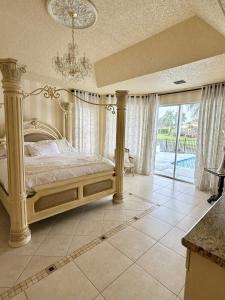 a bedroom with a large bed with a chandelier at Lux 4 bedroom home on lake with pool! in Coral Springs