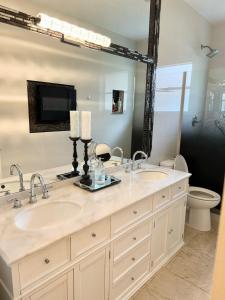 a bathroom with two sinks and a large mirror at Lux 4 bedroom home on lake with pool! in Coral Springs