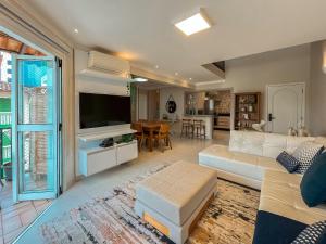 a living room with a white couch and a tv at Riviera - Duplex Lindo Contemporâneo com Enxoval Completo in Riviera de São Lourenço