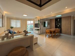 a living room with a table and a dining room at Riviera - Duplex Lindo Contemporâneo com Enxoval Completo in Riviera de São Lourenço