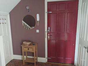 Una puerta roja en una habitación con una mesa y un espejo en Historic Dover Stay with Stunning Castle View, en Dover