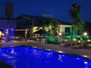 a swimming pool at night with a table and chairs at Hotel Três Palmeiras in Gravatá
