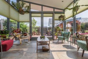 een overdekte patio met stoelen, tafels en ramen bij Casa Mirador Sleep Inn in Almere