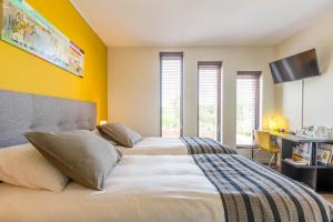 a bedroom with two beds with yellow walls and windows at Casa Mirador Sleep Inn in Almere