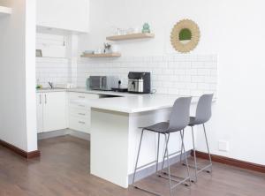 a kitchen with a counter and two stools at The Diplomat Studio by Cape Living in Cape Town +2 photos