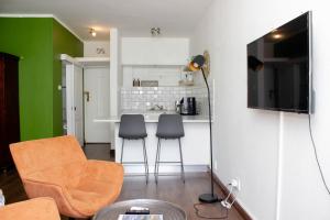 a living room with two chairs and a kitchen at The Diplomat Studio by Cape Living in Cape Town