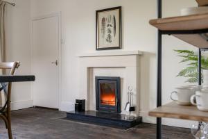 a living room with a fireplace and a table at Historic Riverside House - Village, River Walks & Easy York Access in Cawood +18 photos