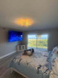 a bedroom with a large bed with a painting on the wall at BEACHFRONT OCEANVIEW BALCONY GAMES POOL 75 TV in Cape Canaveral