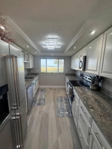 a large kitchen with white cabinets and a large window at BEACHFRONT OCEANVIEW BALCONY GAMES POOL 75 TV in Cape Canaveral