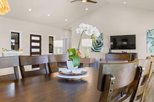 Una mesa de comedor con un jarrón de flores encima. en Ainamalu, en Waikoloa