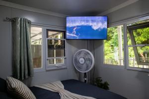 a bedroom with a fan and a tv on the wall at Coqui Tiny House - Unit 1 in Rincon
