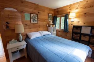 a bedroom with a blue bed and wooden walls at Secluded Cabin With Ocean Access in Seal Cove