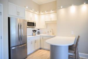 a kitchen with white cabinets and a stainless steel refrigerator at Coastal Luxury Studio One Block to Big Rock in Morehead City +1 photo