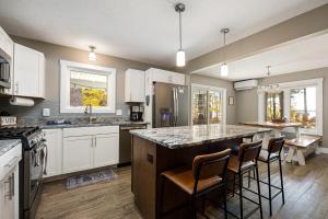 a kitchen with white cabinets and a large island with bar chairs at The Long Lake Escape in Traverse City