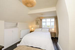a bedroom with a white bed and a window at Historic Riverside House - Village, River Walks & Easy York Access in Cawood