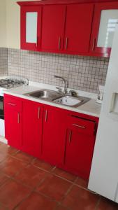 a kitchen with red cabinets and a sink at Hacienda El Palmar D in Vega Baja