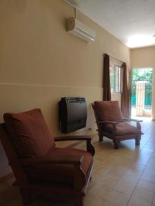 a living room with two chairs and a tv at Cabañas Los Pinos in Potrero de los Funes