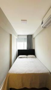 a bed in a room with a window at Apartamento Guarujá, com sacada vista mar! Pé na areia, Lindo! in Guarujá