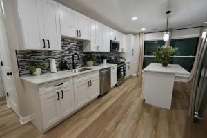 a large kitchen with white cabinets and wooden floors at Modern Stylish Comfort Near Casino and Hwy in East Hazel Crest