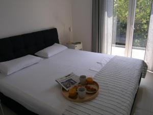 a tray of food on a bed with cups and a magazine at Apartments Mon Amour in Dubrovnik