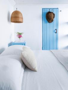 ein weißes Bett mit einem Kissen und einer blauen Tür in der Unterkunft Pousada Vila Bahia in Caraíva + 162 Fotos