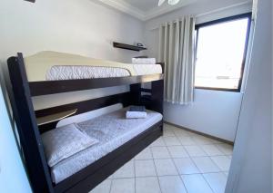 two bunk beds in a small room with a window at Apartamento recantoazul es Conforto Total a 50m do Mar Apartamento Recém-Reformado na Praia de Castelhanos, ES, para 7 Pessoas Aconchegante e Completo, com 3 Quartos e 1 Suíte in Anchieta