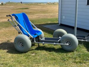 Una silla de ruedas azul con ruedas grandes aparcada en el césped. en Nordsee Oase 50 0 N, en Wangerland